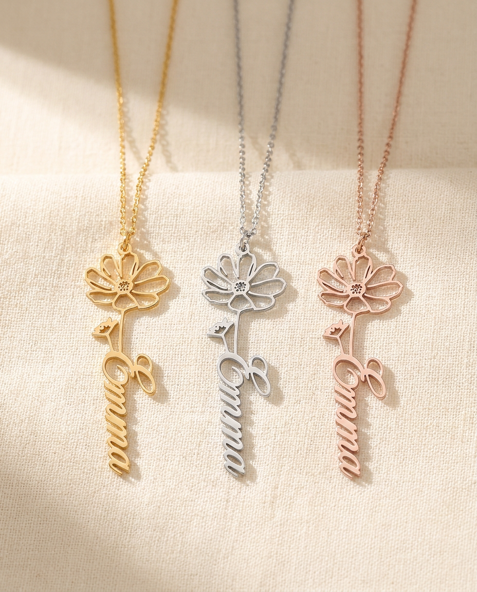 Three Emma flower pendants side by side in gold-tone, silver-tone and rose-tone on cream linen