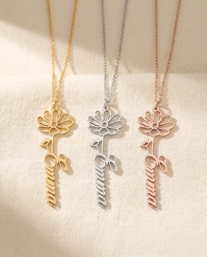 Three Emma flower pendants side by side in gold-tone, silver-tone and rose-tone on cream linen