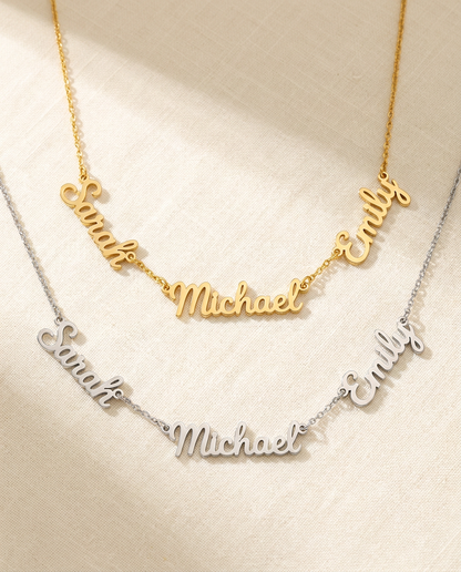 Two necklaces reading Sarah, Michael and Emily in linked script names, a gold-tone one above a silver-tone one, on cream linen
